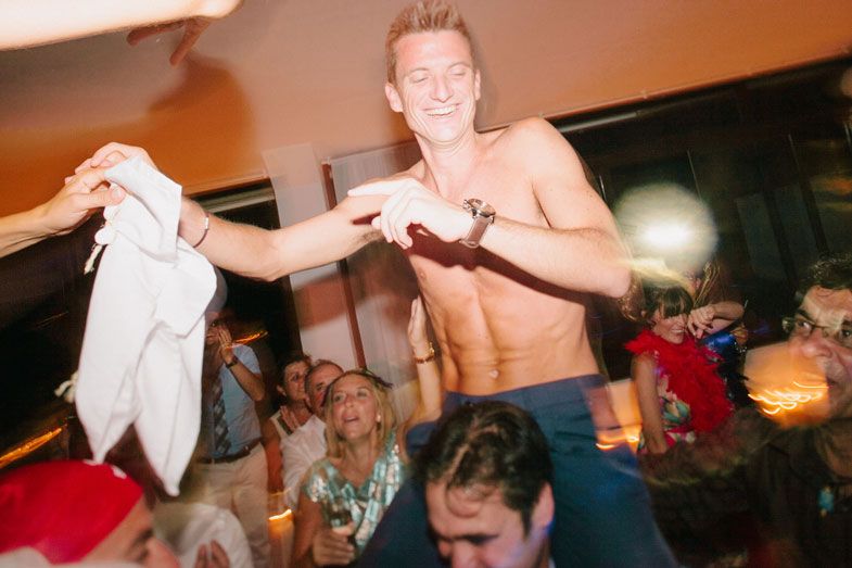 Shirtless guest celebrates enthusiastically amid the wedding reception crowd.