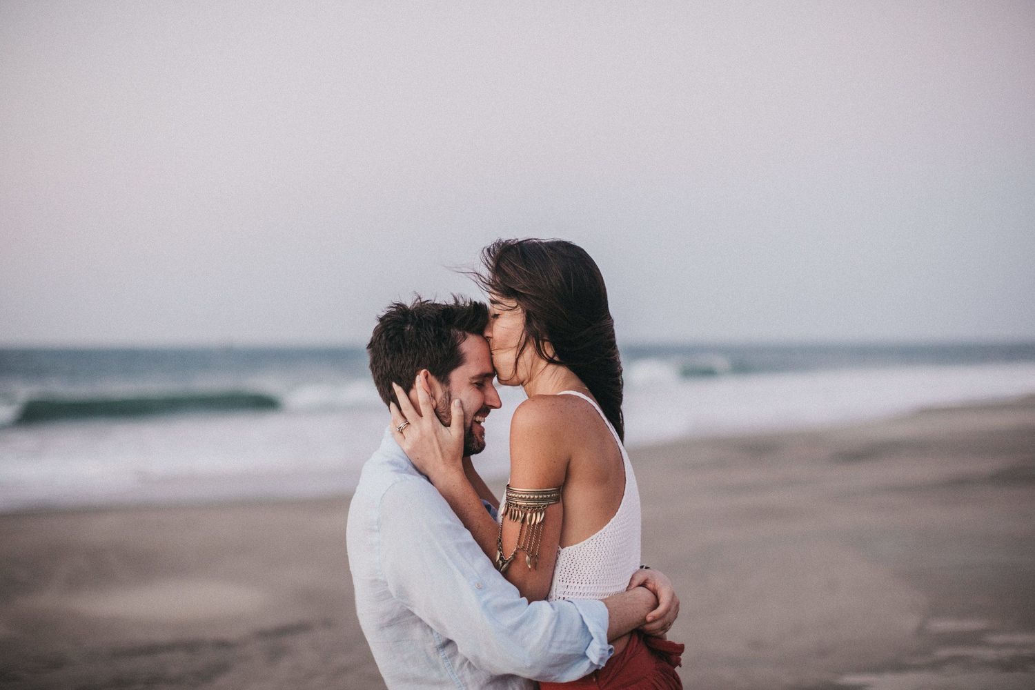 Intimate beach portrait of a couple sharing a tender moment at sunset.