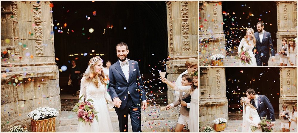 Wedding celebration with guests throwing confetti outside a stone church entrance.