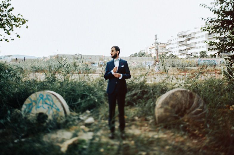 Person in formal attire standing in an outdoor setting with vintage decor.