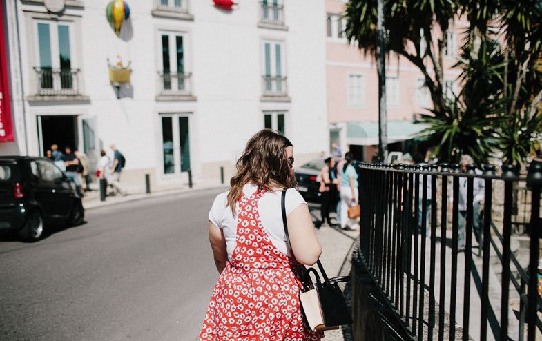 A red polka dot dress stands out against white buildings on a charming European street.