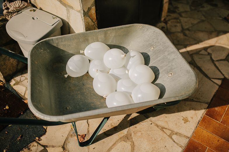 White water balloons arranged in a metal wheelbarrow.