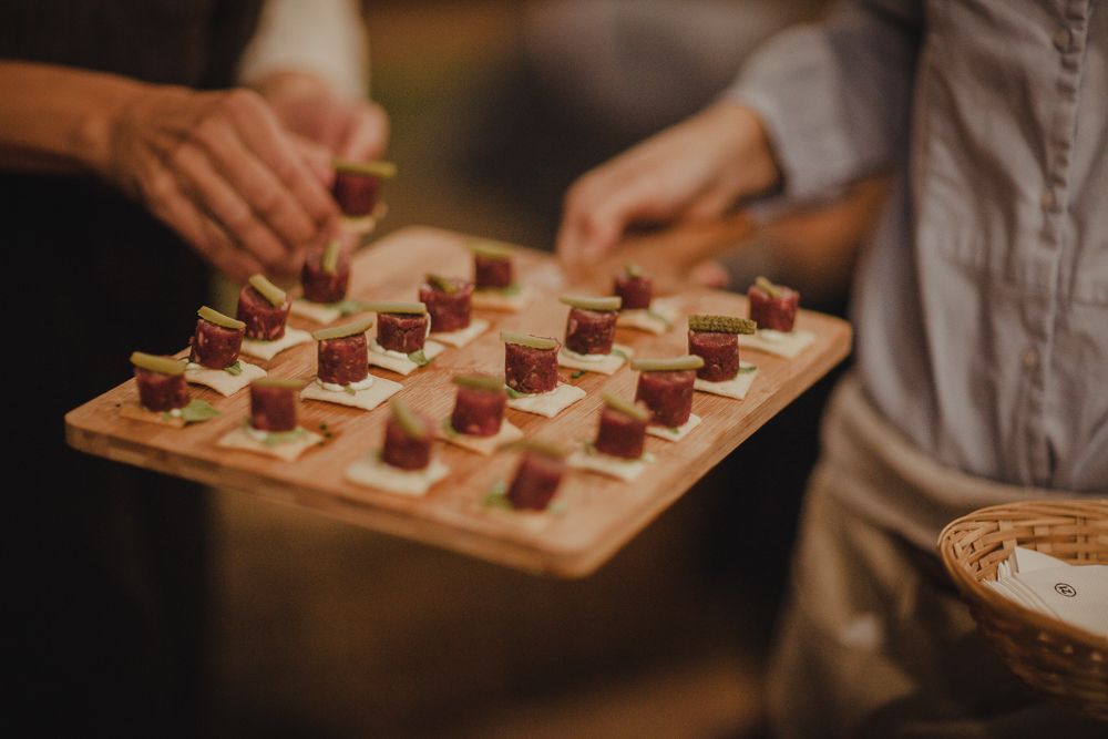 Small bite-sized desserts arranged on wooden serving board at catered event.