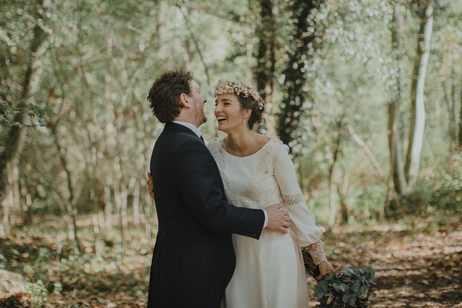 Romantic moment between newlyweds in a sunlit forest setting.