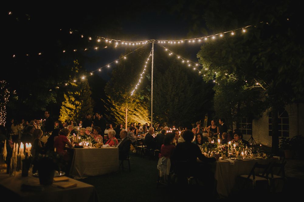 String lights illuminate an outdoor wedding reception creating a magical evening ambiance.