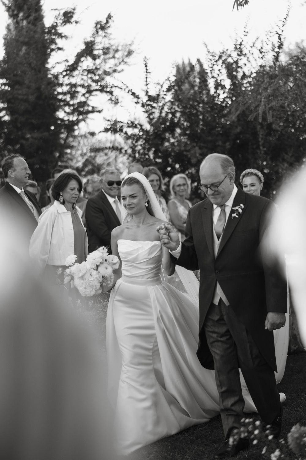 Wedding party members walking together outdoors in formal attire.