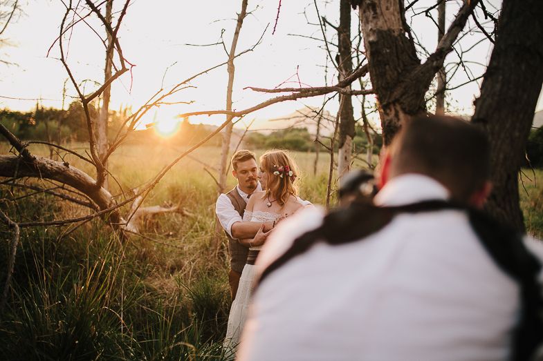 Photographer captures a romantic moment between a couple during a golden sunset in nature.