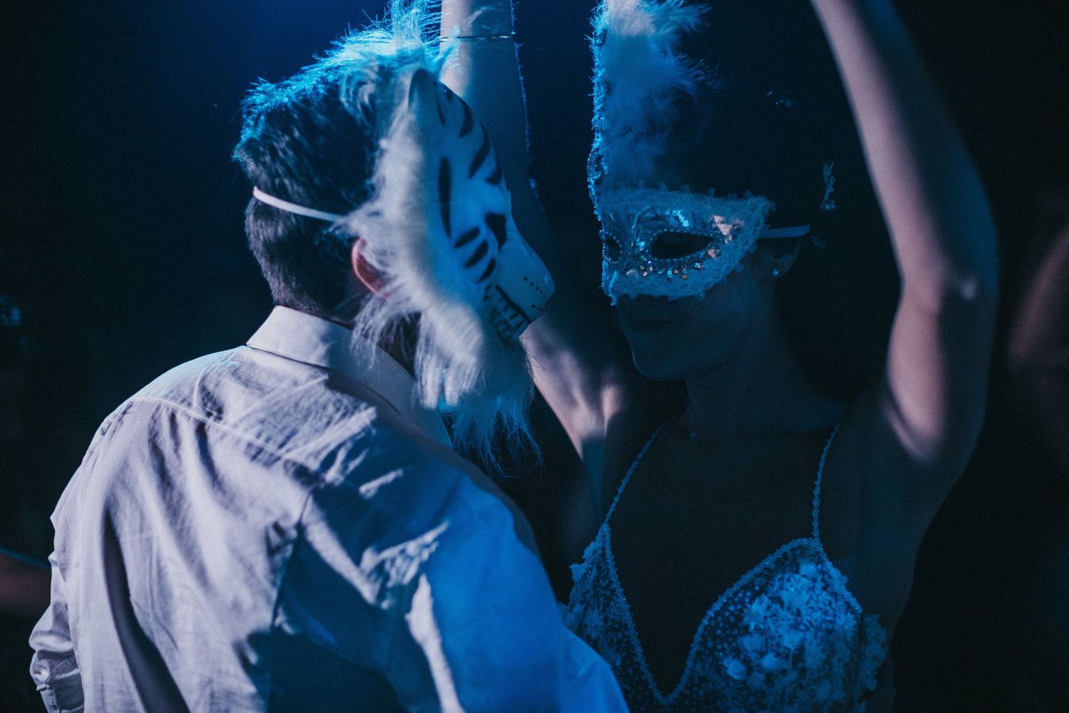 Party scene with blue lighting and raised hands creating an energetic atmosphere.