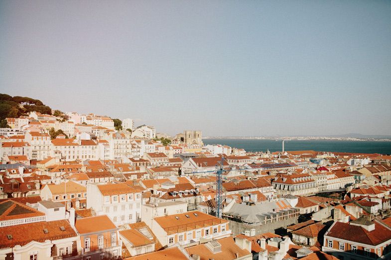 Aerial view of Lisbon's terracotta rooftops and coastal landscape.