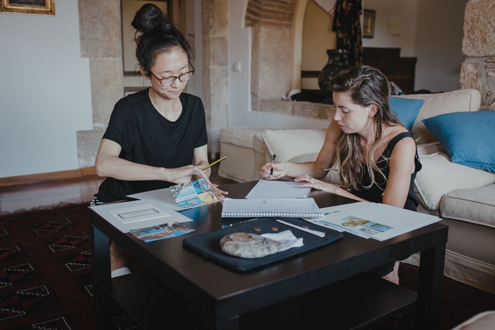 Two people sit at coffee table reviewing documents together.