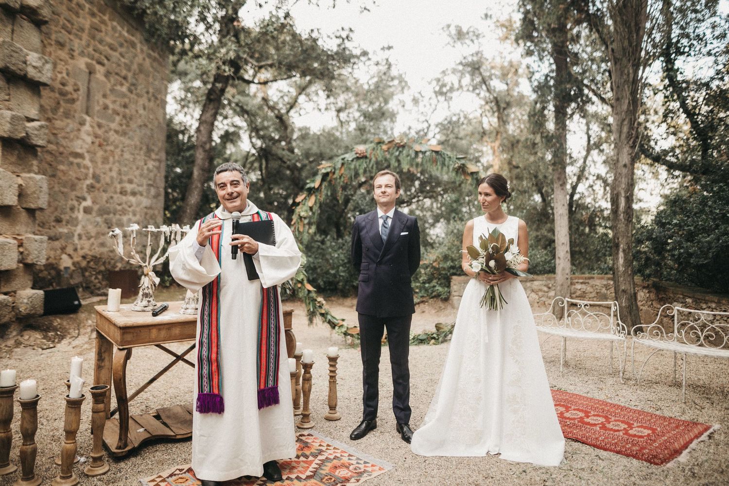 Outdoor wedding ceremony setup with rustic stone wall backdrop and red carpet.