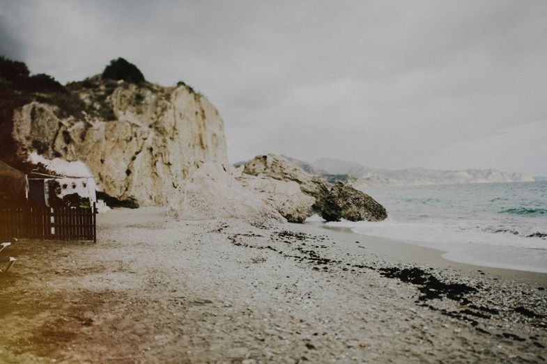 Rugged coastal cliffs and beach with waves breaking along a rocky shoreline.