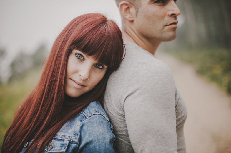 A couple in casual attire posing together on a path.