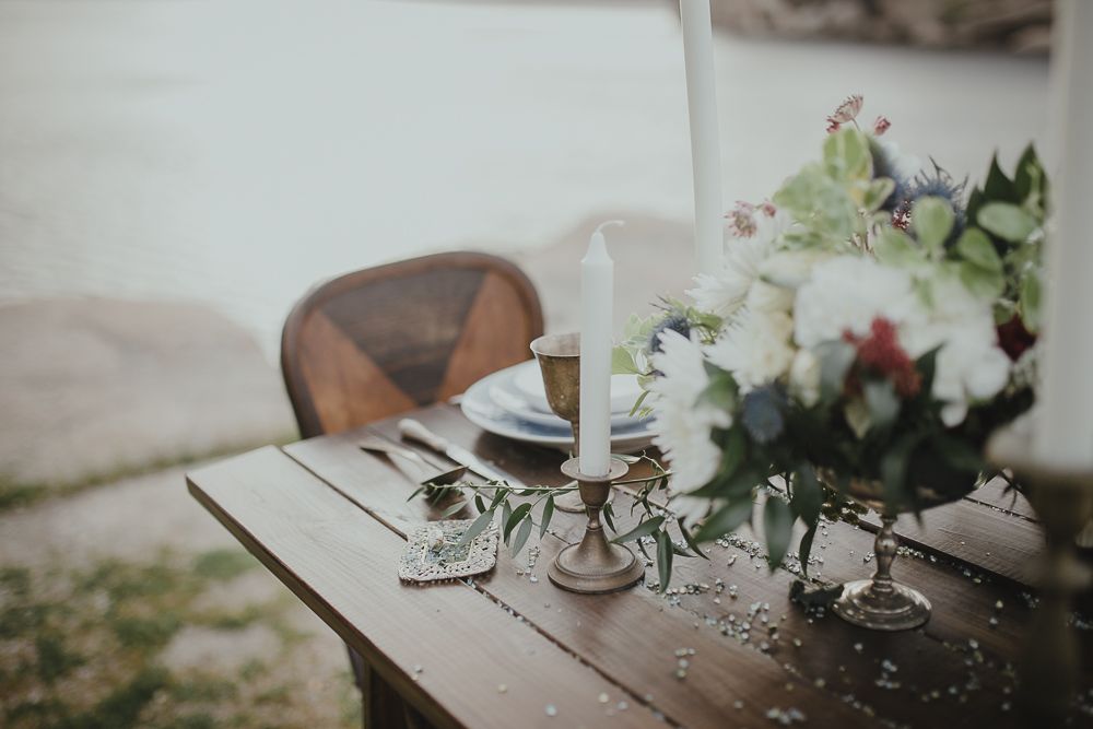 Close-up of romantic table setting with white floral arrangement and candlesticks.