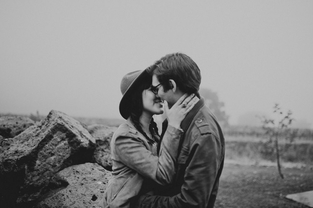 An intimate black and white portrait captured against a misty natural backdrop.