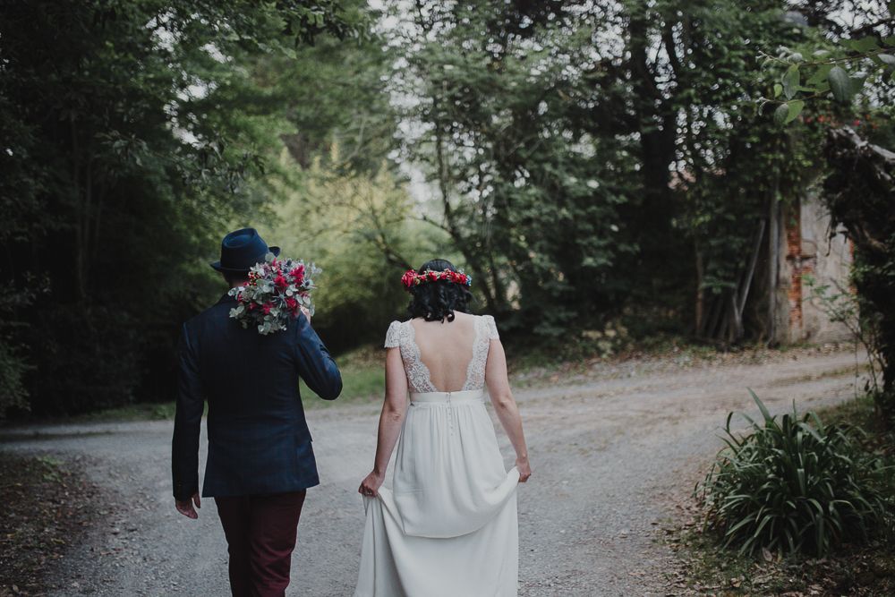 A couple walking away on a forest path during their wedding day.