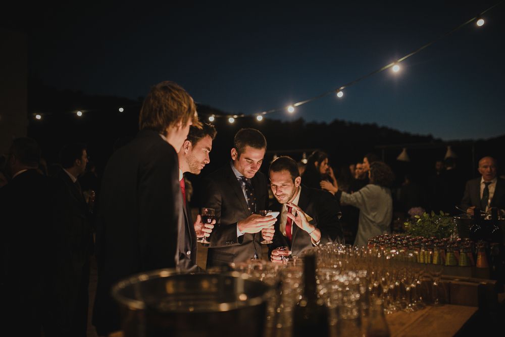 Evening outdoor party with string lights and guests mingling at bar area.
