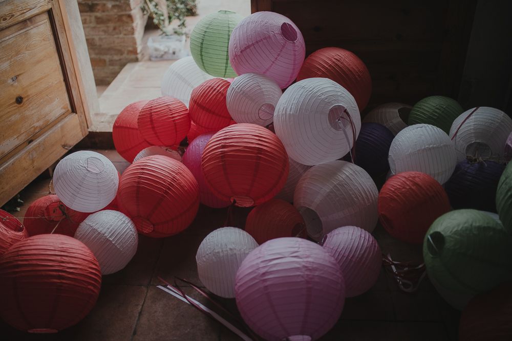 Colorful paper lanterns in red, pink, and white clustered together indoors.
