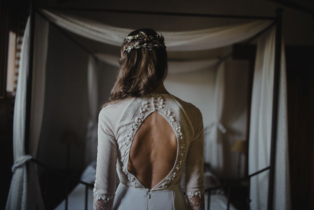 Close up of wedding dress showing intricate lace details and dramatic open keyhole back design.