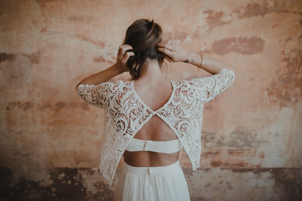Close-up of a wedding dress back detail showing intricate lace patterns and cross-strap design.