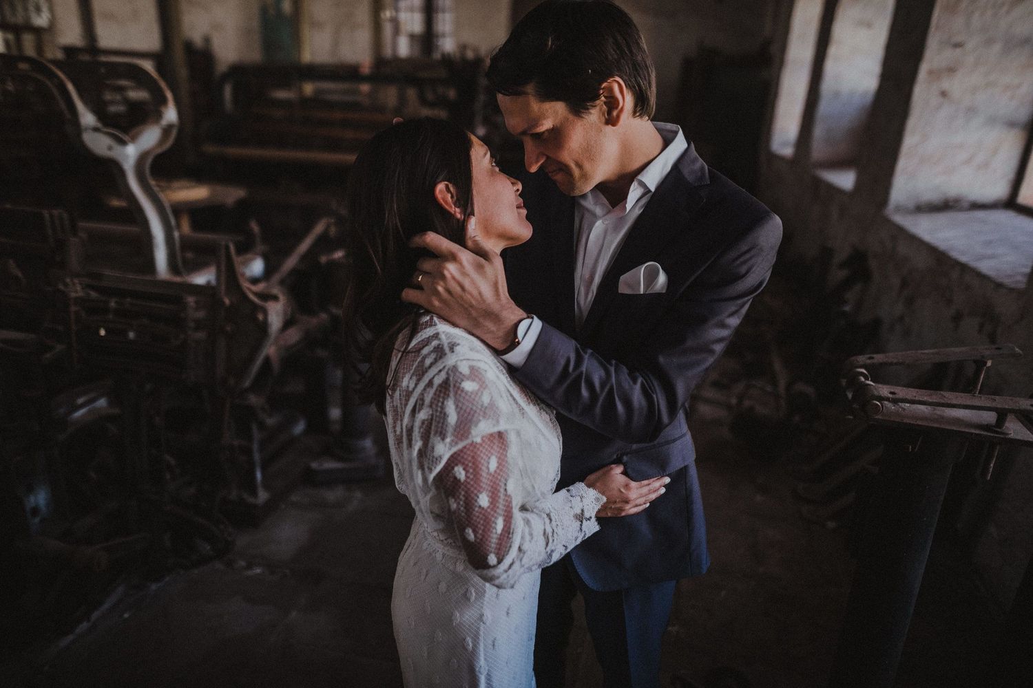 Intimate moment between couple in formal wear inside historic industrial building.