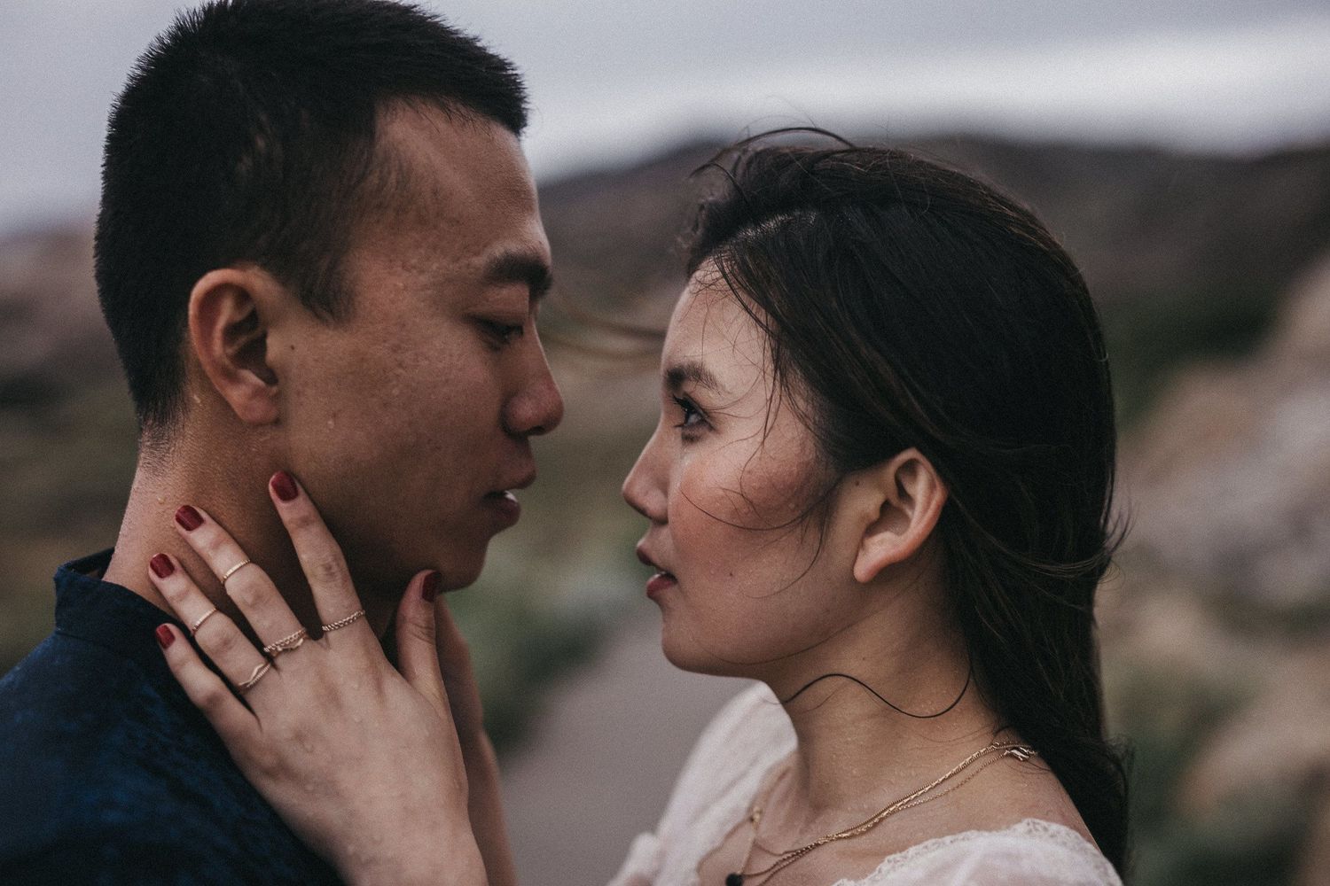 Close-up of couple in tender moment against moody natural backdrop.