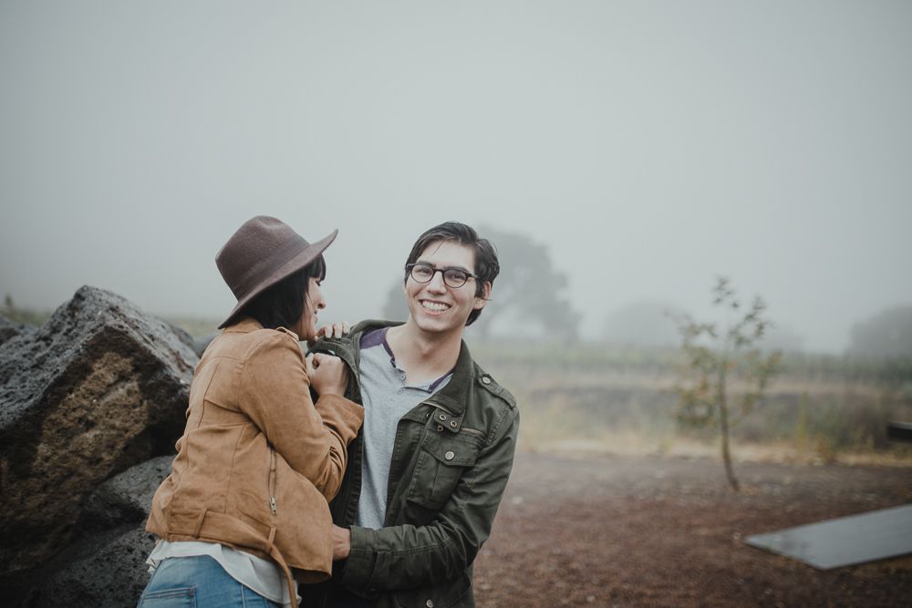 A joyful outdoor moment shared between two people on a foggy day.