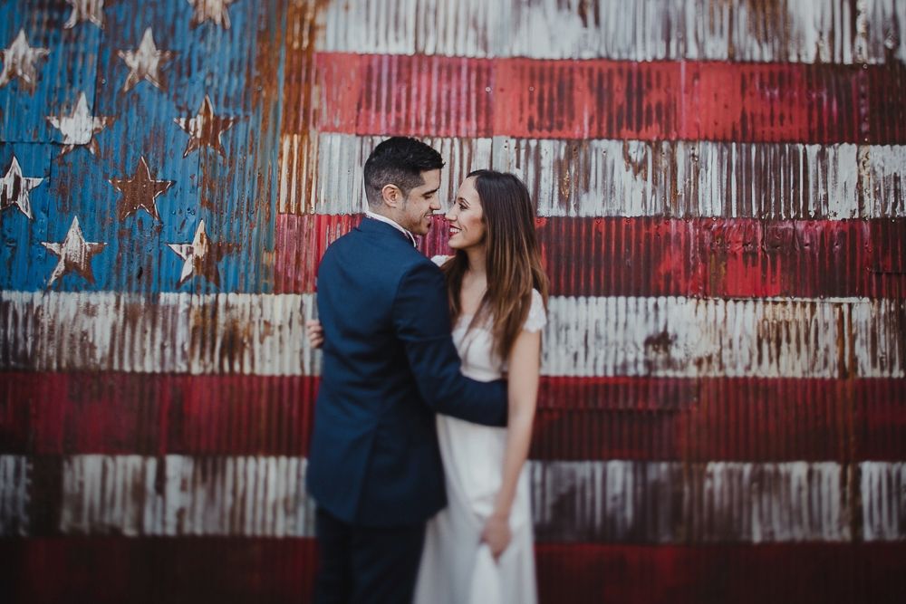 A romantic moment against a rustic American flag backdrop.