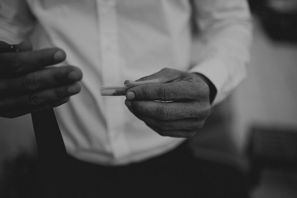 Close-up black and white shot of hands holding a small object in a formal setting.