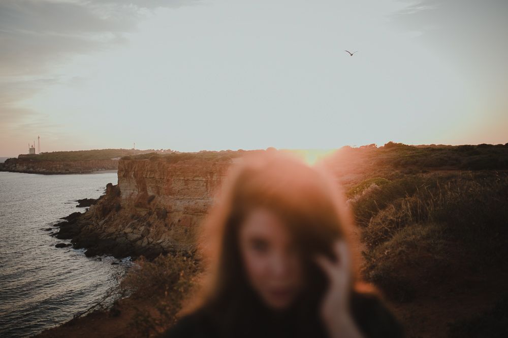 Artistic silhouette photograph of coastline and cliffs during golden hour.