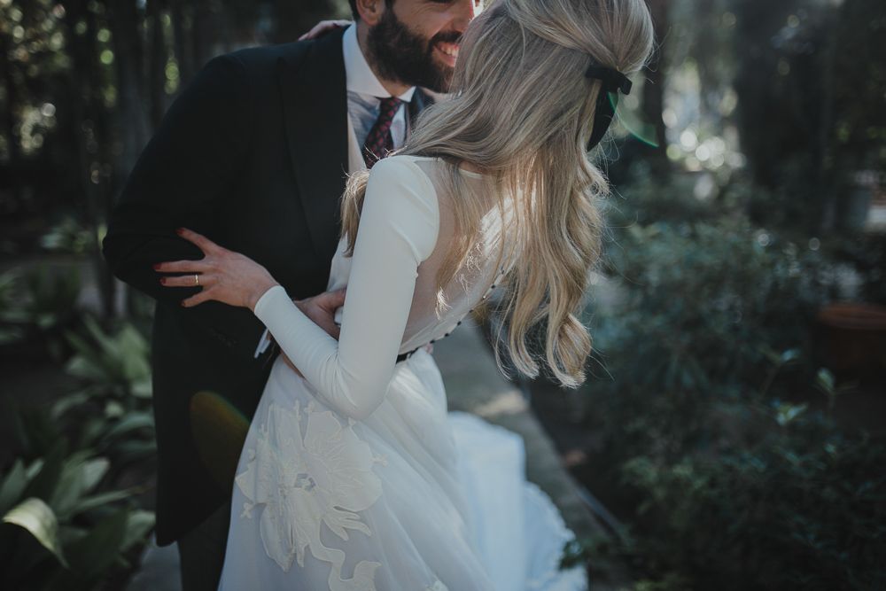 Candid moment of a couple in wedding attire sharing a playful embrace in a lush garden setting.