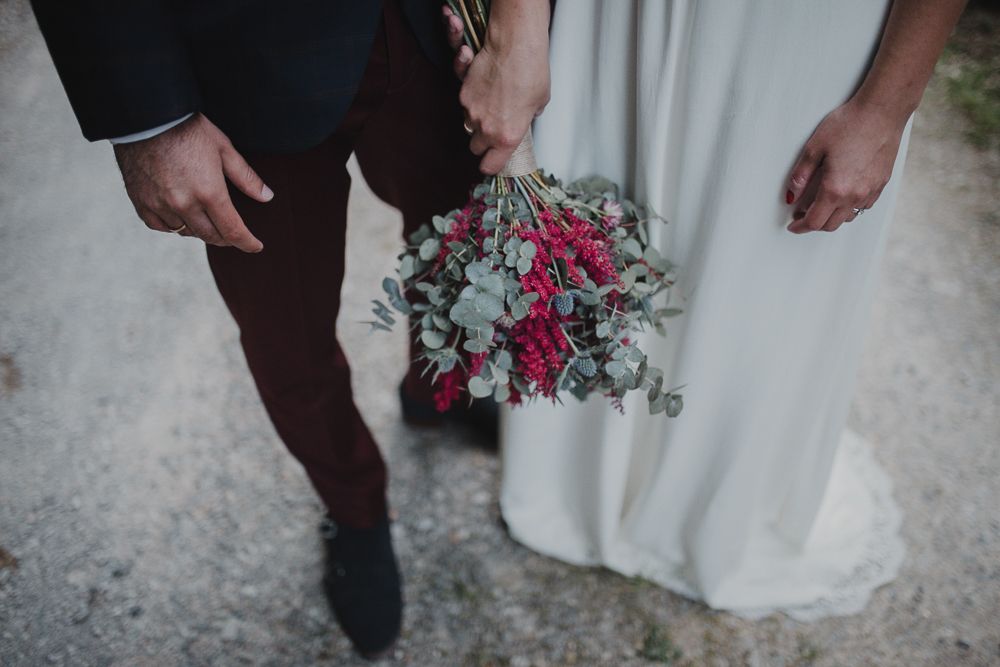 Close-up of wedding couple holding a pink and green floral bouquet.
