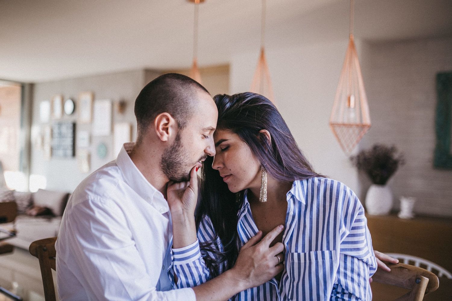 An intimate indoor portrait of a couple sharing a tender moment.