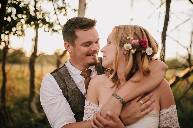 A couple shares an intimate romantic moment in a rustic outdoor setting at sunset.