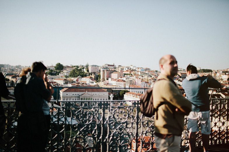 Tourists at a viewpoint overlooking a European city panorama.