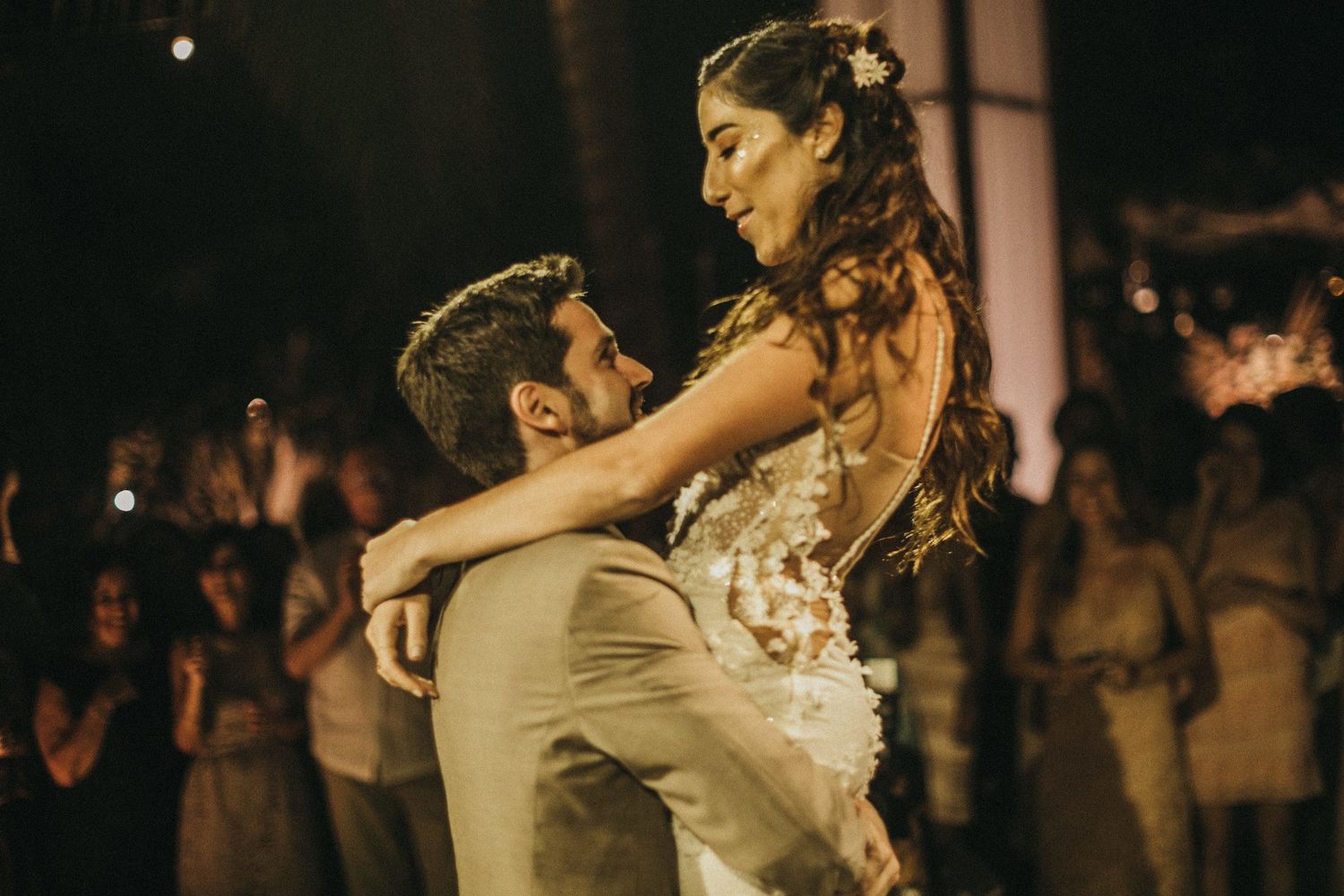 A couple shares an intimate dance moment at their wedding reception surrounded by guests.