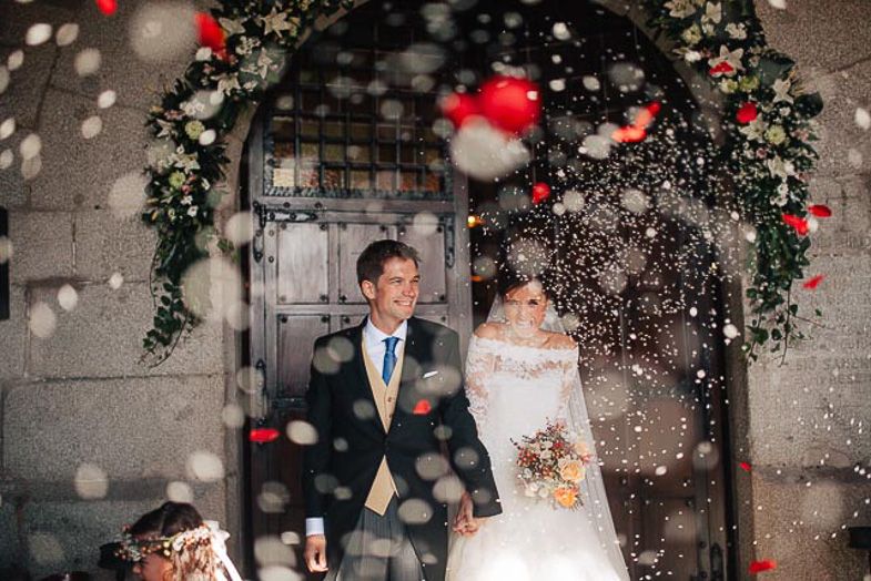Wedding couple under floral arch with snow effect and red bokeh lights.
