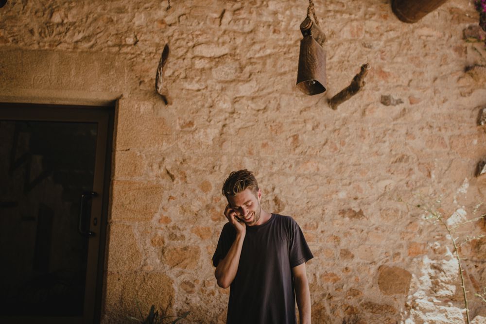 Person in dark shirt stands against textured stone wall.