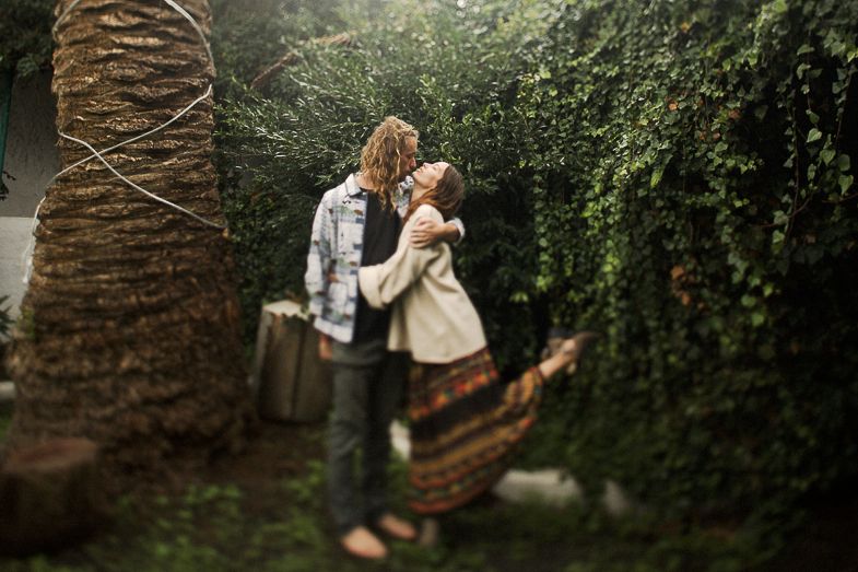 A romantic outdoor scene against lush greenery and a palm tree trunk.