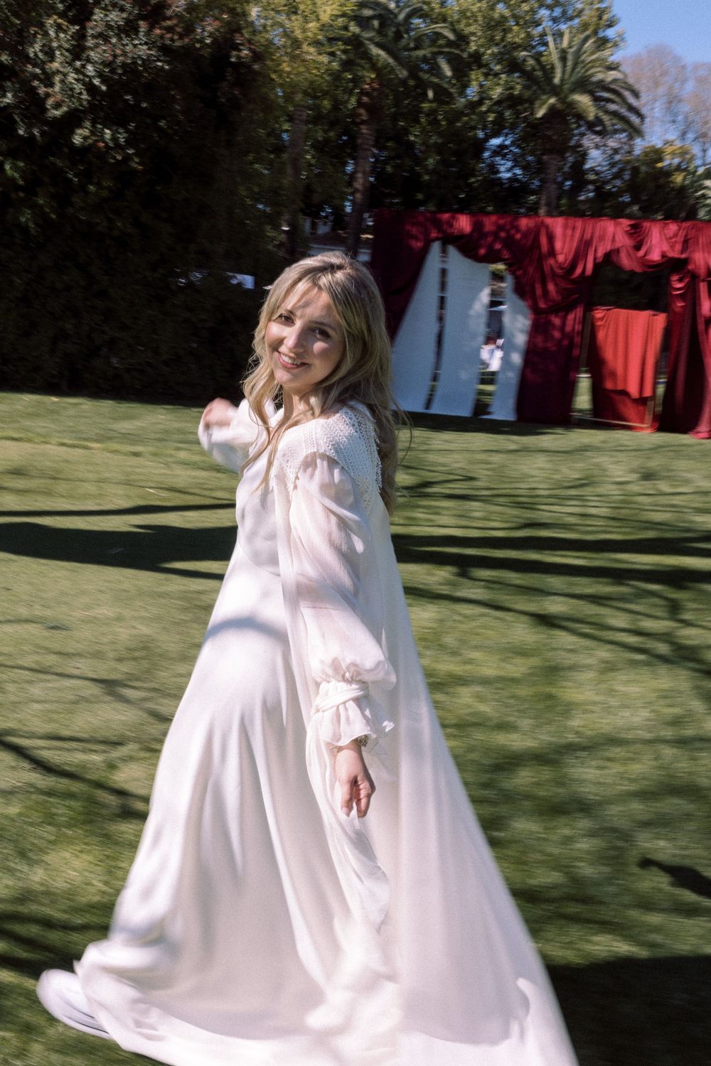 A joyful spin in a flowing white dress on a sunny garden lawn.