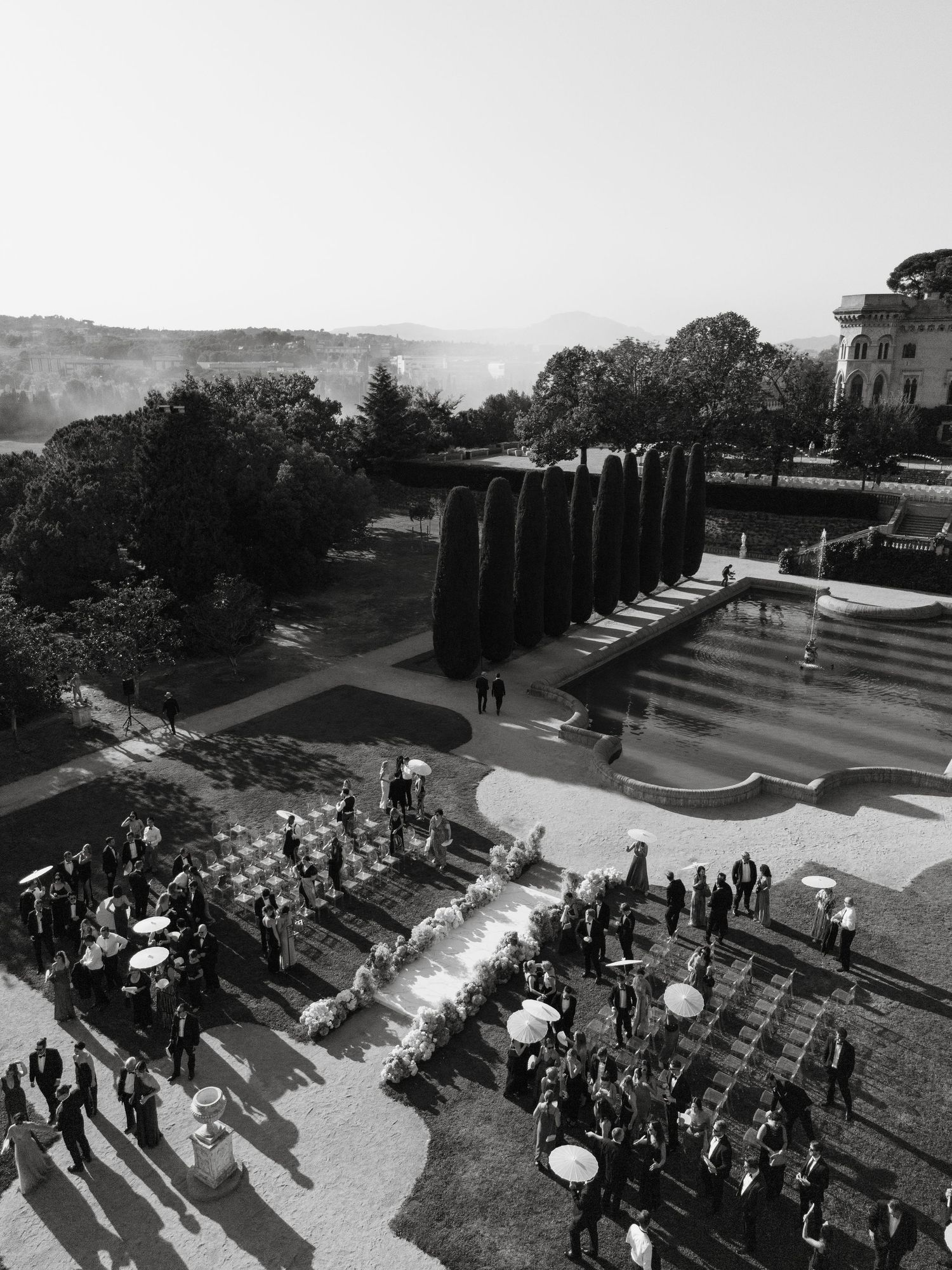Black and white panoramic sequence showing a crowd gathering on outdoor amphitheater steps during a sunny day.