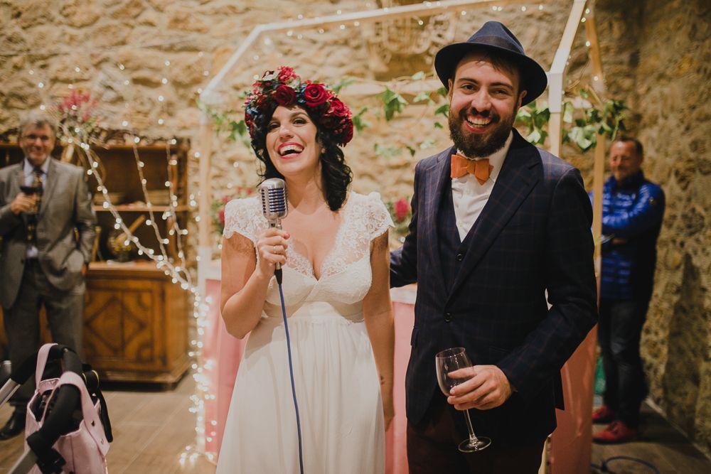 Joyful moment during wedding reception with rustic decor and string lights.