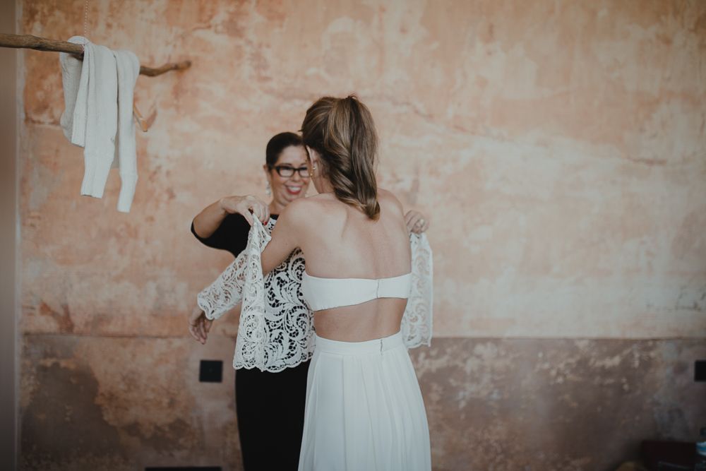 Two people making final adjustments to a white formal dress.