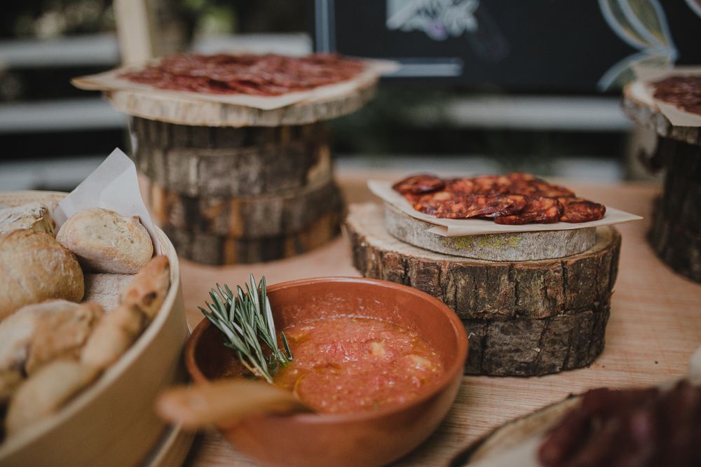 Artisanal meats and dips arranged on wooden serving boards at a catering display.