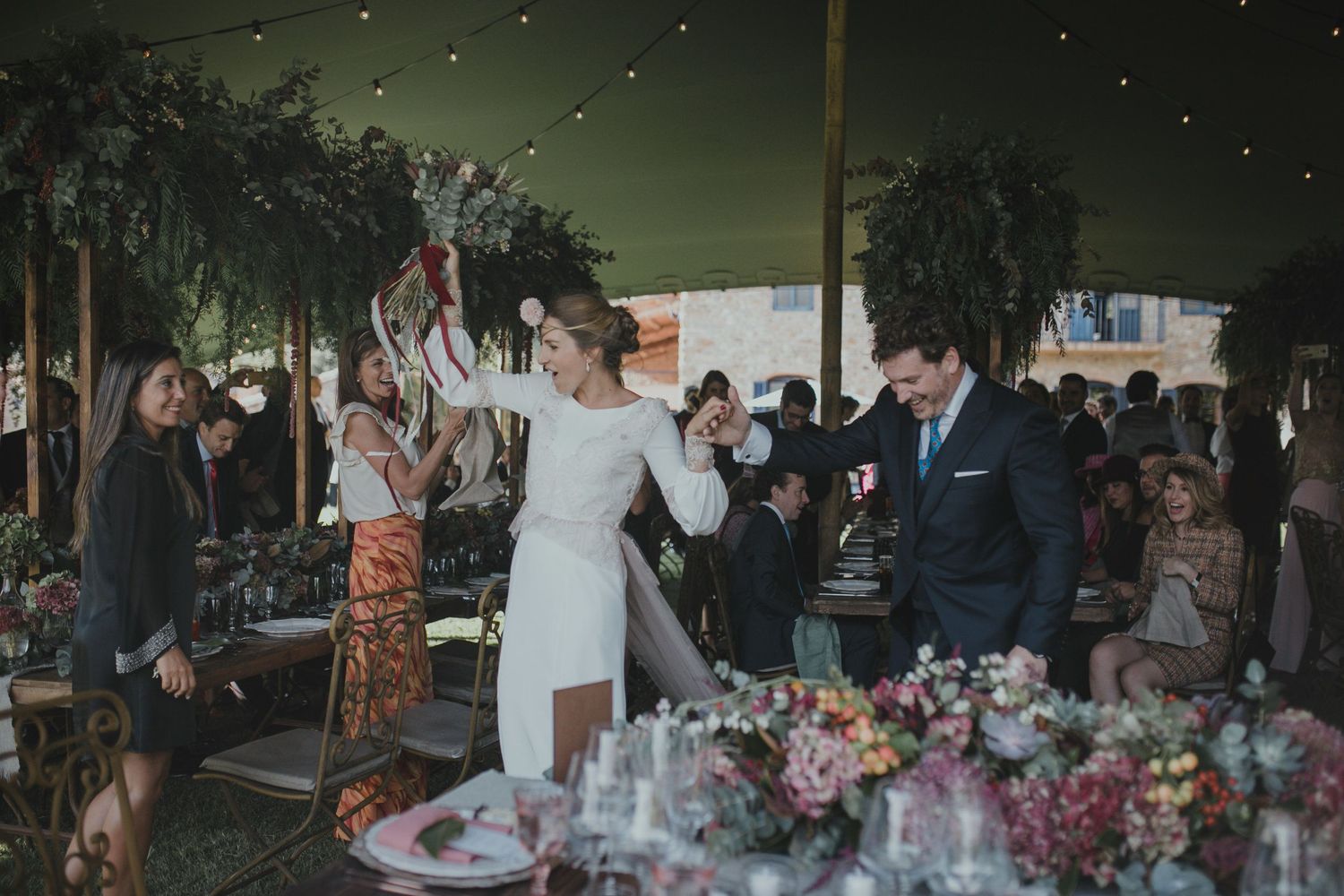 A celebratory moment under string lights at an evening outdoor wedding reception.