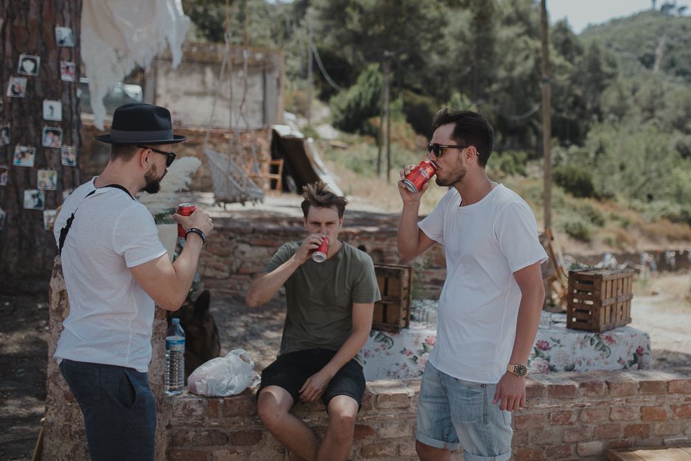 Three friends hanging out and talking on a rustic stone wall in an outdoor setting.