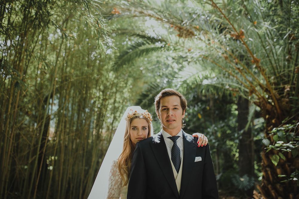 Wedding portrait of a couple standing in a lush bamboo forest setting.