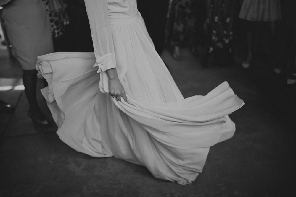 A flowing white wedding dress catches movement in a dramatic black and white photo.