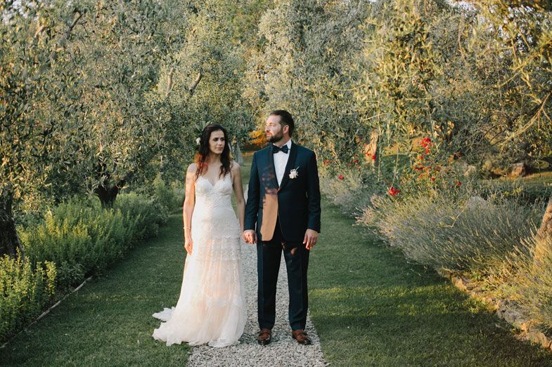 A couple shares a romantic moment in an olive grove garden on their wedding day.