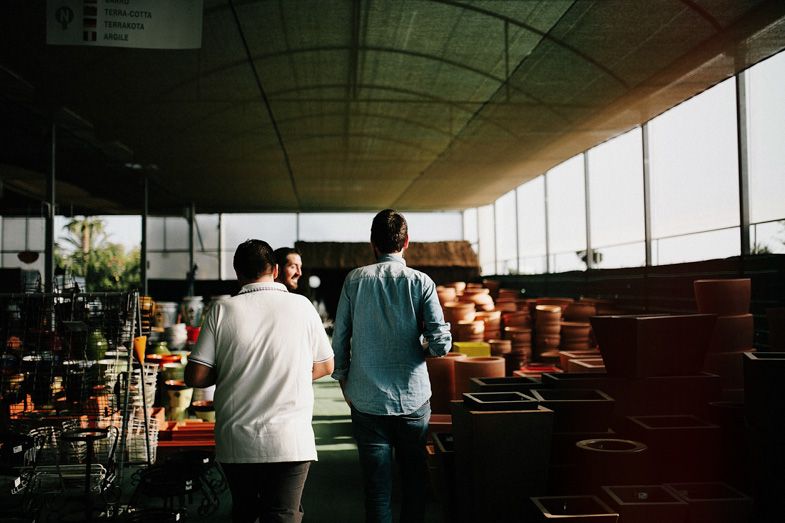 Two people standing in covered area overlooking terracotta pots.